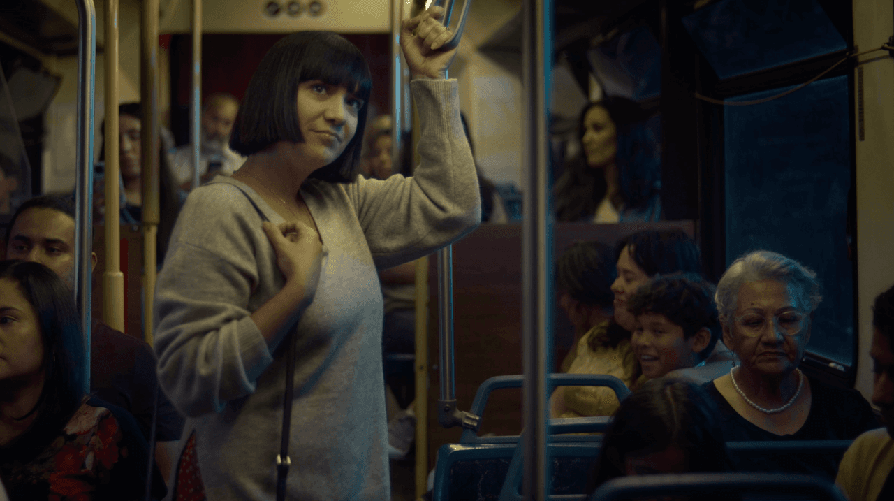 A woman smiles slightly as she rides a subway train